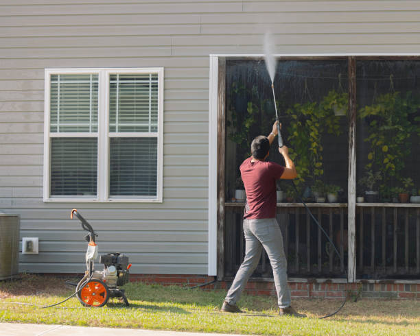 man pressure washing vinyl siding house